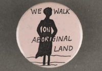 A light pink badge with the silhouette of a woman and the words we walk on aboriginal land over laid.