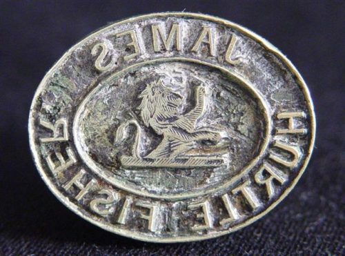 A small metal sealing stamp with the name James hurtle fisher embossed into it. In the centre is a small depiction of a lion.