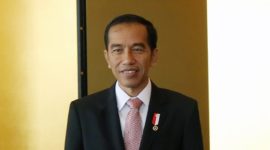 Head and shoulders of Indonesian president Joko Widodo. He is wearing a black suit, white shirt, and pale red tie.