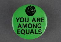 green badge with a picture of a black rose and the slogan 'you are among equals'