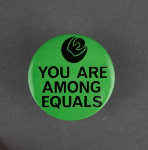 green badge with a picture of a black rose and the slogan 'you are among equals'